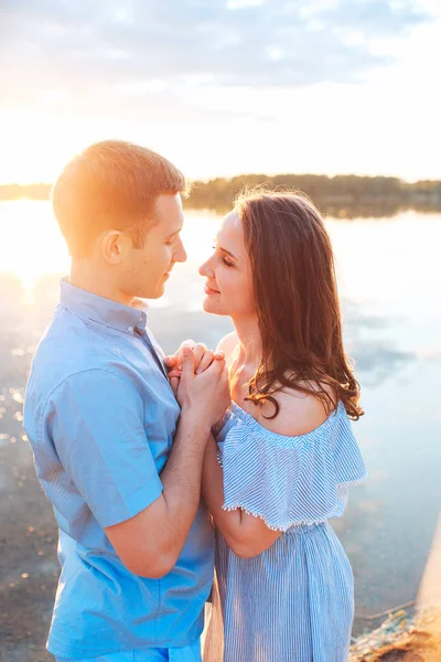 Jeune beau couple amoureux rester et embrasser sur la plage au coucher du soleil. Couleurs douces et ensoleillées . — Photo