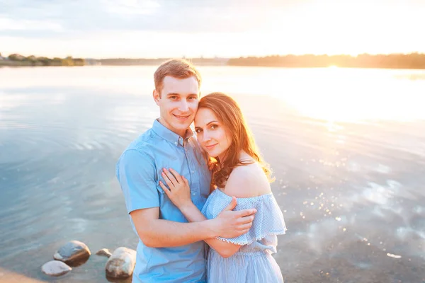 Jonge mooie paar in liefde blijven en huging op het strand op de zonsondergang. Zachte zonnige kleuren. — Stockfoto