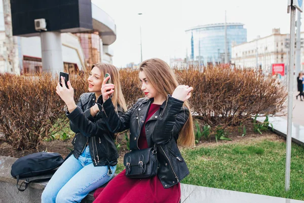 Närbild sommaren livsstil porträtt av två bästa vänner skrattar och pratar utomhus på gatan i centrum. Klädd i snygg svart jacka, klänning, solglasögon. Njuter av tiden tillsammans. — Stockfoto