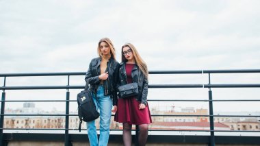 Kadınlar cityscape içinde birlikte birkaç. İki neşeli güzel moda Kız çatıda. Güzel şehir manzaralı