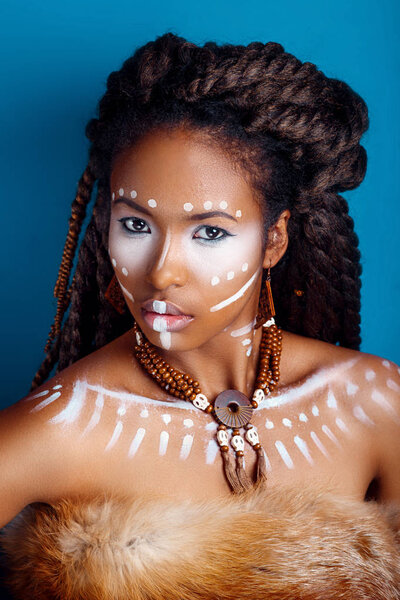 African style . Attractive young woman in ethnic jewelry . close up portrait of a woman with a painted face. Creative makeup and bright style.