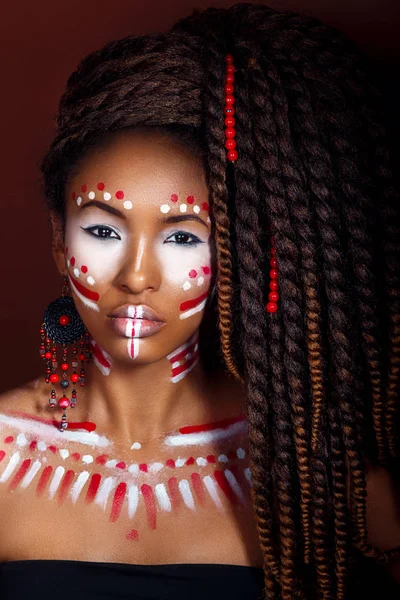 Mujer de estilo africano. Mujer joven atractiva en joyería étnica. primer plano retrato de una mujer con una cara pintada. Maquillaje creativo y estilo brillante . — Foto de Stock