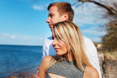 Mutlu çift deniz arka plan üzerinde. Mutlu genç çift gülüyor ve sahilde sarılma