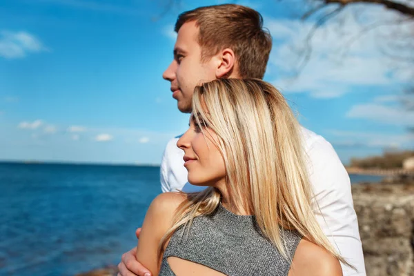 幸福的夫妇的海面背景。快乐的年轻夫妇笑着拥抱在沙滩上 — 图库照片