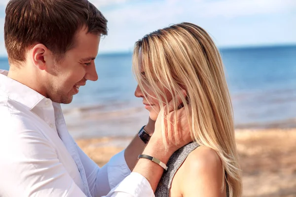 Schönes Paar, das einander ansieht und sich am Strand umarmt — Stockfoto