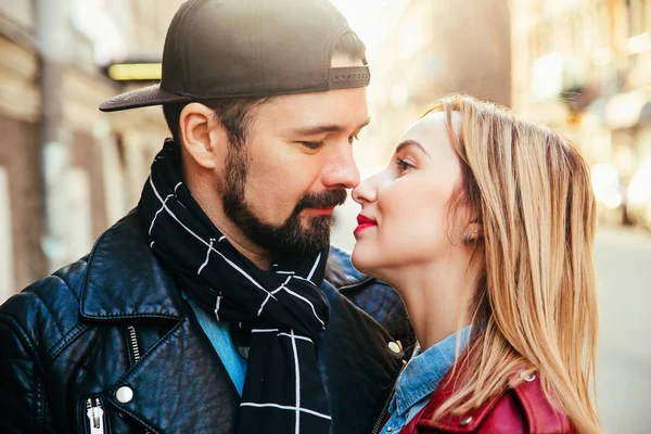 Outdoor fashion portrait of stylish couple kissing on sunset at the city street, wearing biker leather total black rock n roll look