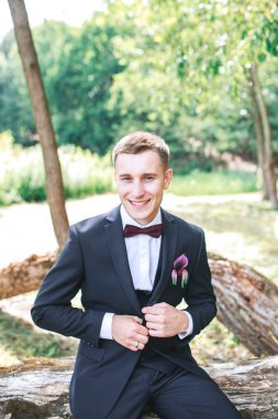 Zarif damat siyah kostüm ve mor papyon. Düğün gününde damat. Muhteşem gülümseyen damat.