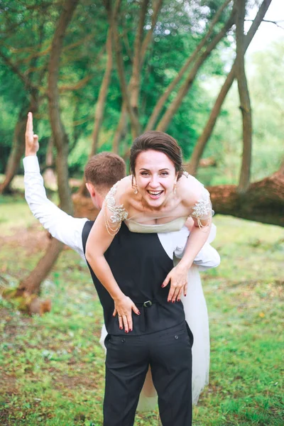Portret van een knappe jongeman met aantrekkelijke vrouw op zijn rug buitenshuis. Bruid en bruidegom — Stockfoto