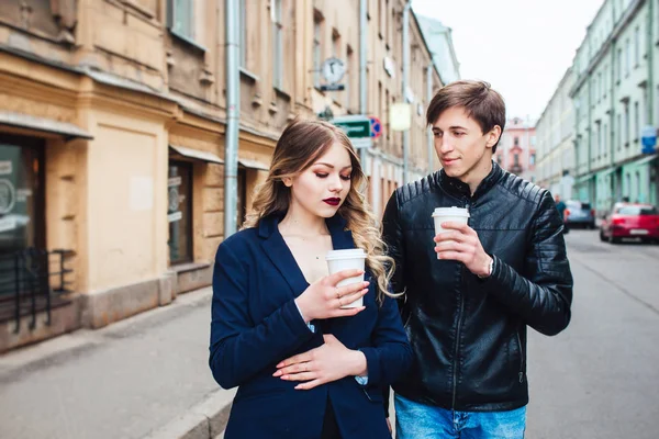 Portrait of a happy romantic couple with coffee walking outdoors in european city — Stock Photo, Image