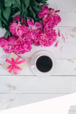 Bir fincan kahve, pembe peonies desen ve hediye kutusu ahşap arka plan üzerinde