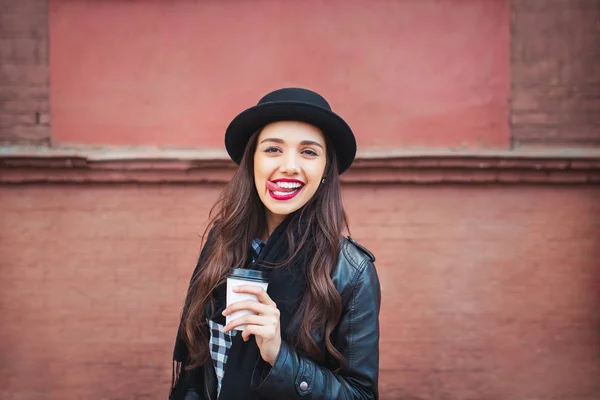 Молодая стильная женщина на городской улице пьет кофе и веселится — стоковое фото