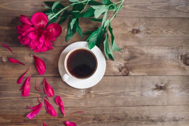 Bir fincan kahve, kırmızı peonies desen ahşap arka plan üzerinde. Günaydın. Kadın ya da anneler günü arka plan. Üstten Görünüm