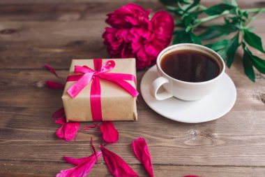 Bir fincan kahve, kırmızı peonies desen ve hediye kutusu ahşap arka plan üzerinde. Günaydın