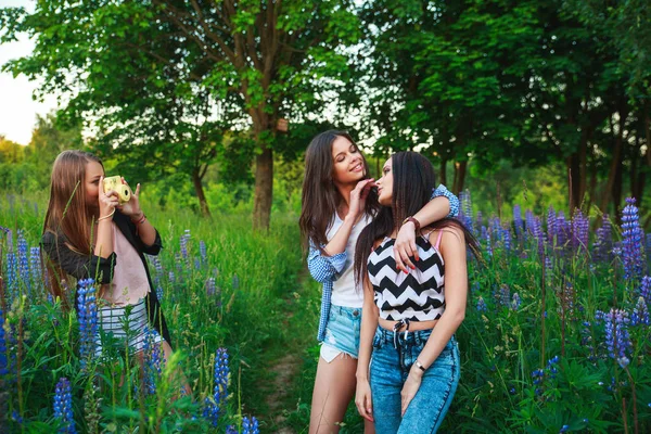 Tre ragazze hipster bionde e brune scattare autoritratto sulla macchina fotografica polaroid e sorridente all'aperto. Ragazze che si divertono insieme nel parco . — Foto Stock