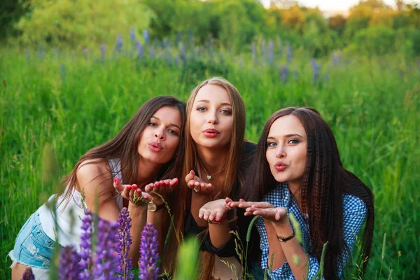 Drie mooie jonge gelukkig meisjes beste vrienden verzend een kus van lucht, glimlachen en lachen — Stockfoto