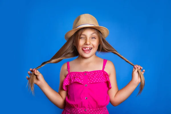 Πορτραίτο κοριτσιού χαριτωμένο ροζ φόρεμα και καπέλο διασκεδάζοντας σε μπλε φόντο. Καλοκαιρινές διακοπές και τα ταξίδια έννοια — Φωτογραφία Αρχείου