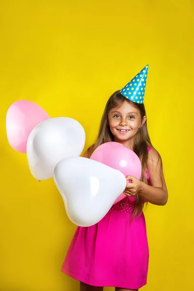 Portret dziewczynki w kapeluszu ze stron na jej urodziny. Szczęśliwa dziewczyna z kolorowych balonów — Zdjęcie stockowe