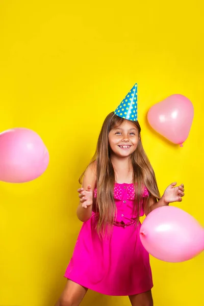画室肖像，一个小女孩在她生日那天穿党的帽子。五颜六色的气球快乐的女孩 — 图库照片
