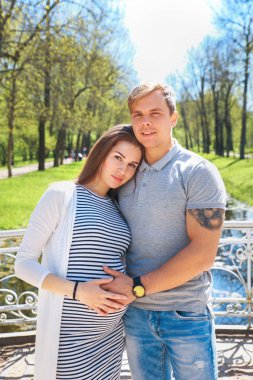 Yakışıklı ve güzel hamile eşi sarılma ve park dururken gülümseyen