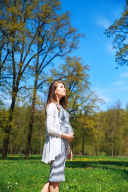 Hamile kadın parkta poz veriyor.