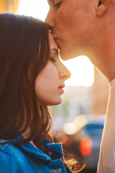 Молода пара цілується на заході сонця в місті  . — стокове фото
