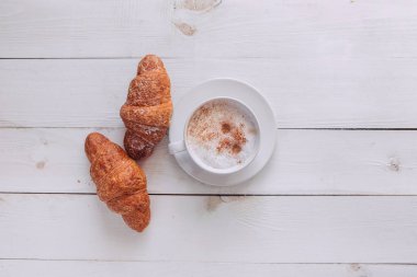 Kahve kupa ile kruvasan ve notlar Günaydın yukarıdan beyaz rustik masada sıcak ve lezzetli bir kahvaltı, vintage tonda