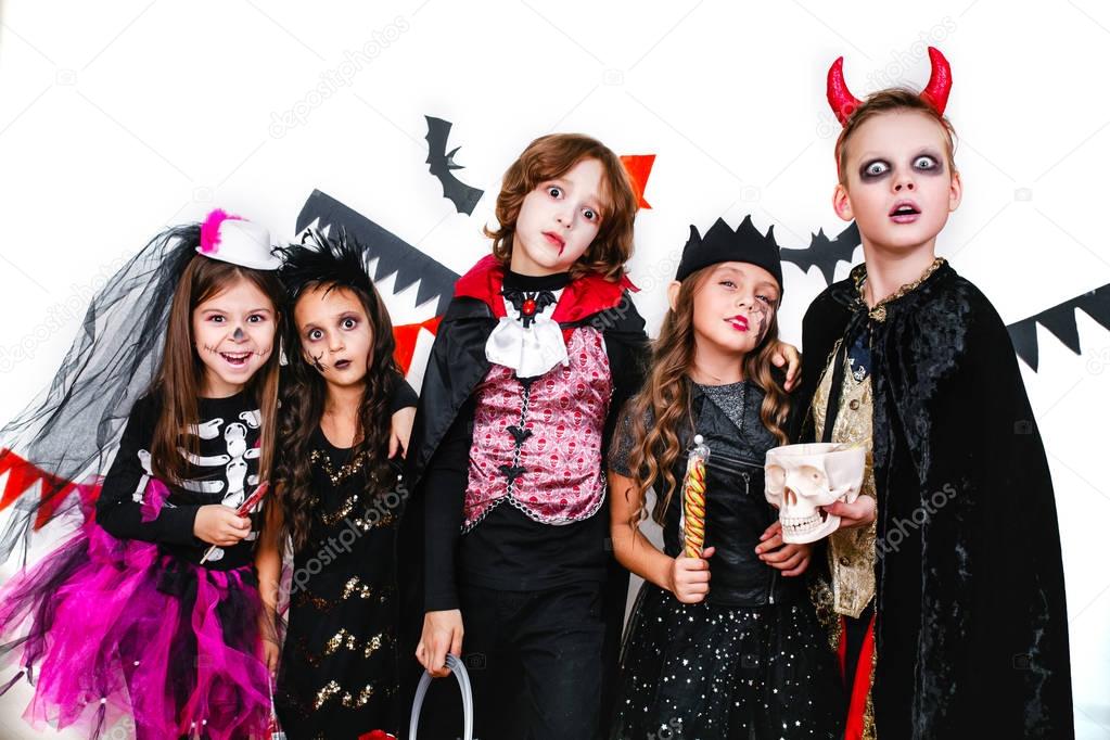 Children in halloween costumes show funny faces