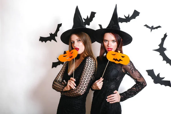 Due donne felici in costumi di Halloween strega nera con zucca sulla festa su sfondo bianco — Foto Stock