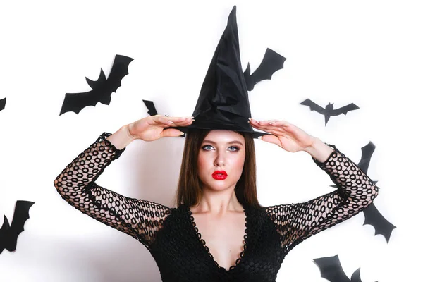 Gelukkig gotische jonge vrouw in halloween kostuum heks met hoed permanent en lachend op witte achtergrond — Stockfoto