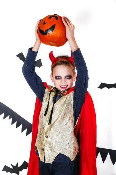 Vakantie halloween. grappige kind in carnaval kostuums duivel met pompoen op een witte achtergrond — Stockfoto