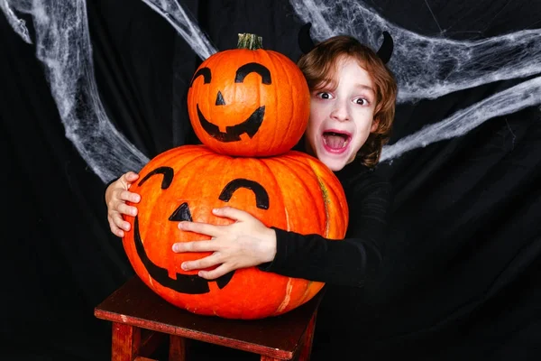 Een jonge jongen in halloween kostuum met pompoenen plezier — Stockfoto