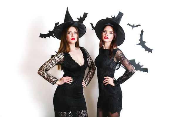 Twee gelukkige sexy vrouwen in het zwart heks halloween kostuums op partij op witte achtergrond — Stockfoto