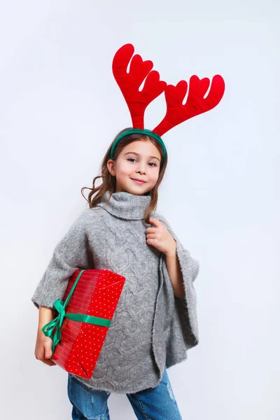 Feliz niña sonriente con regalo de Navidad box.Christmas concepto. Sonriente chica divertida en cuernos de ciervo en el estudio . —  Fotos de Stock