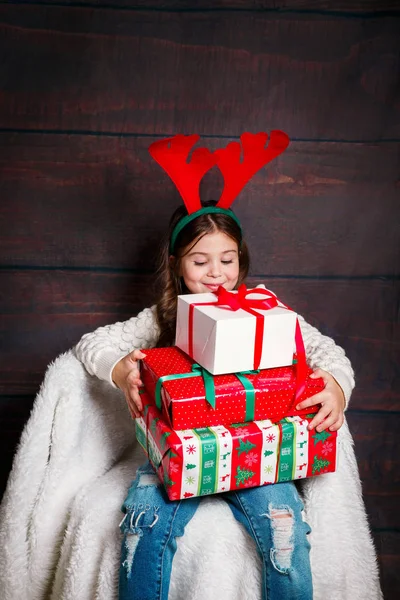Feliz niña sonriente con cajas de regalo de Navidad.. concepto de Navidad. Sonriente niño divertido en cuernos de ciervo en el estudio . —  Fotos de Stock