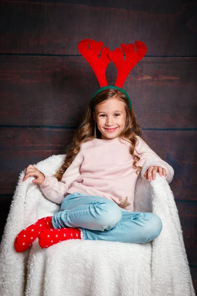 Рождественская идея. Улыбающийся смешной ребенок в оленьих рогах в студии . — стоковое фото