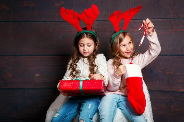 Две счастливые маленькие улыбающиеся девочки с рождественскими подарочными коробками на деревянном фоне. С Рождеством и Новым годом!  . — стоковое фото