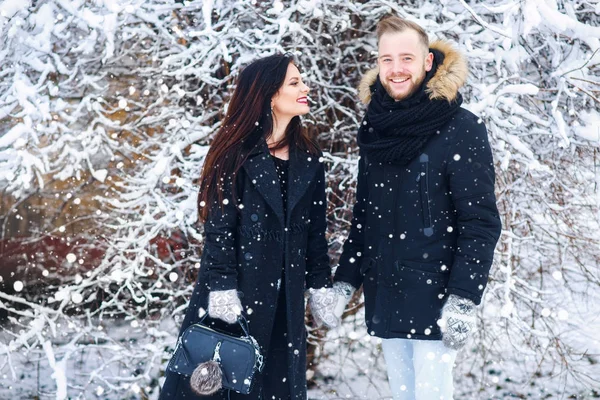 Bonito casal jovem segurando a mão um do outro e sorrindo no parque de inverno de neve — Fotografia de Stock