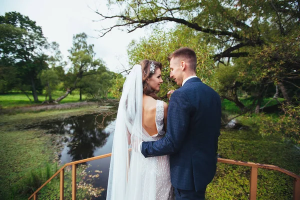 Casamento casal romântico no parque no dia do casamento. noivo abraçando noiva ao ar livre — Fotografia de Stock