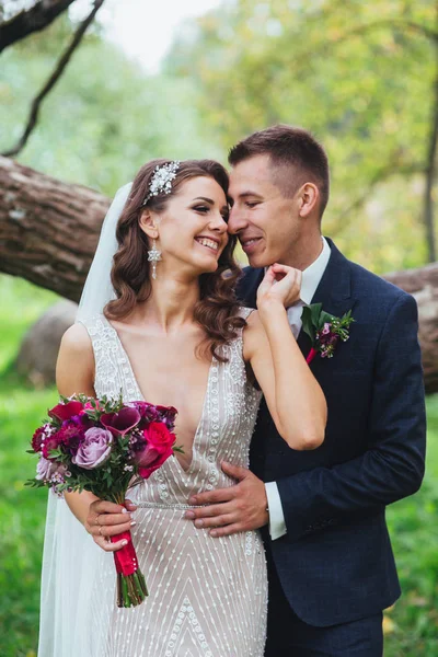 Bruden och brudgummen embracing i parken — Stockfoto