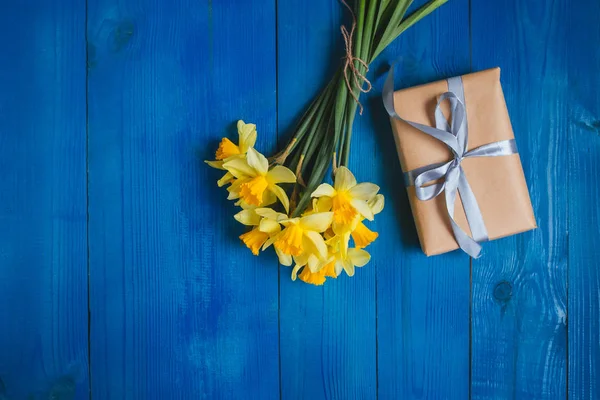 De kaart van de groet van de bloemen. Voorjaar Pasen achtergrond met narcissen boeket en cadeau — Stockfoto