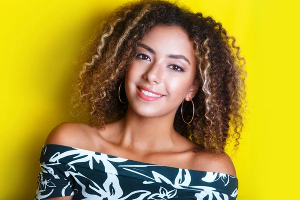 Retrato de beleza da jovem menina afro-americana com penteado afro. Menina posando no fundo amarelo, olhando para a câmera . — Fotografia de Stock