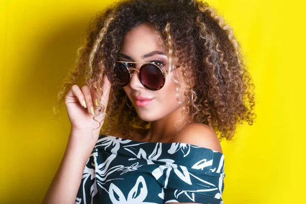 Retrato de beleza da jovem menina afro-americana com penteado afro. Menina posando no fundo amarelo, olhando para a câmera. Estúdio . — Fotografia de Stock