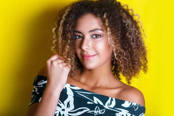 Retrato de beleza da jovem menina afro-americana com penteado afro. Menina posando no fundo amarelo, olhando para a câmera . — Fotografia de Stock