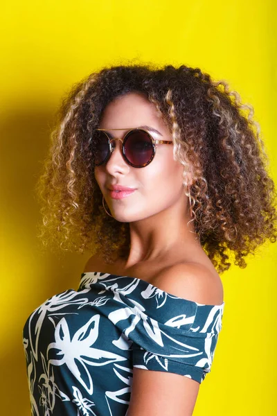 Beauty portrait of young african american girl with afro hairstyle. Girl posing on yellow background, looking at camera. Studio shot. — Stock Photo, Image