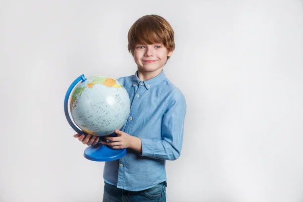 Счастливый маленький мальчик держит глобус. Возвращение в школу и счастливое время — стоковое фото