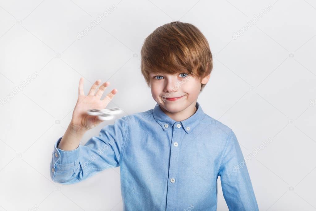 Young boy holding popular fidget spinner toy - close up portrait. Happy smiling child playing with Spinner