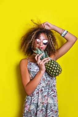 Moda yaz portre gülümseyen afro Amerikan kız güneş gözlüğü ve ananas sarı arka plan üzerinde