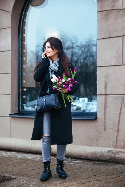 Young girl walking on an old european city street with a bouquet of lilies in her hand — Stock Photo, Image