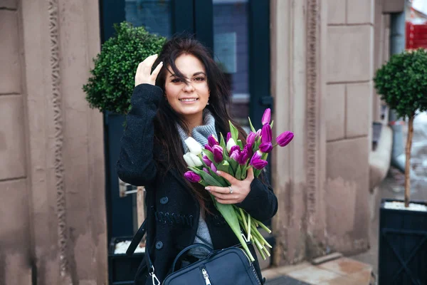 Giovane ragazza che cammina su una vecchia strada della città europea con un mazzo di gigli in mano — Foto Stock