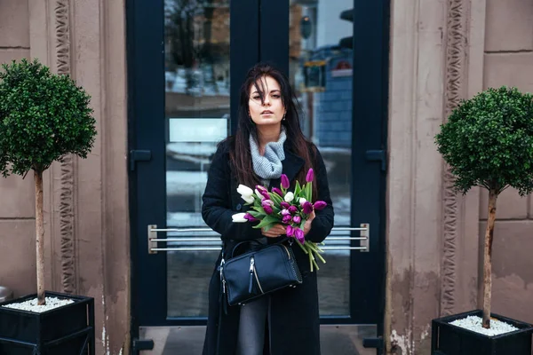 Giovane ragazza che cammina su una vecchia strada della città europea con un mazzo di gigli in mano — Foto Stock